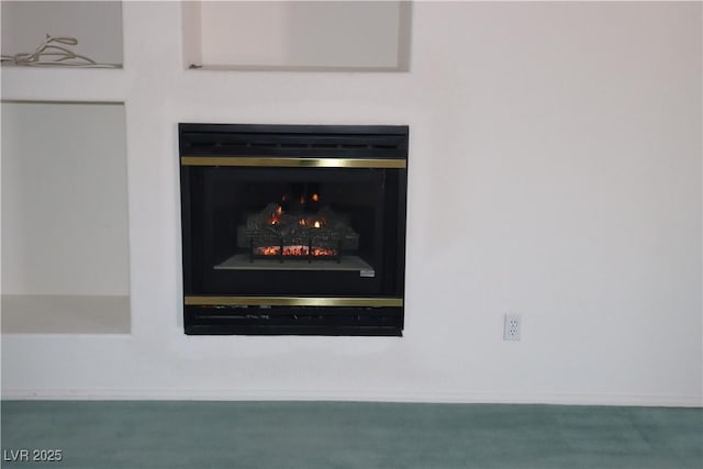 interior details featuring baseboards, a lit fireplace, and carpet flooring