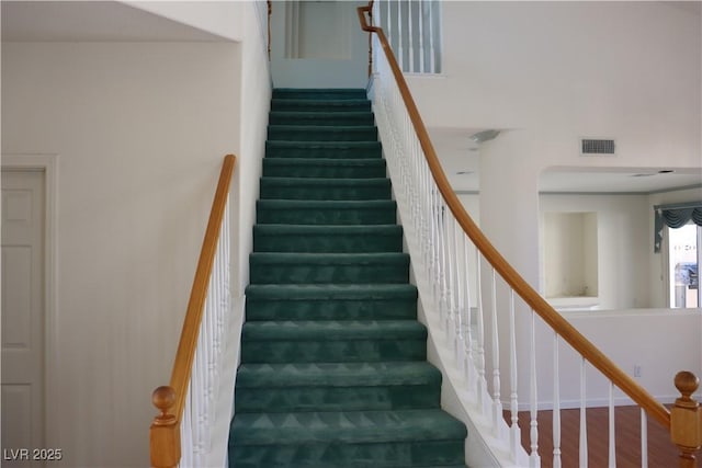 stairway with visible vents and wood finished floors