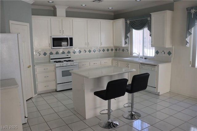 kitchen featuring ornamental molding, light tile patterned flooring, white cabinets, white appliances, and a sink