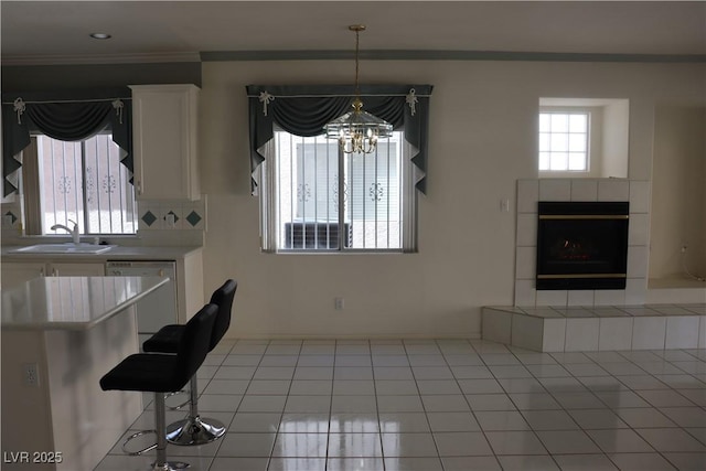 unfurnished dining area featuring crown molding, a fireplace, a chandelier, and a sink