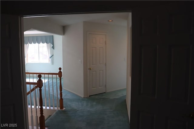 hallway featuring an upstairs landing, baseboards, and carpet floors