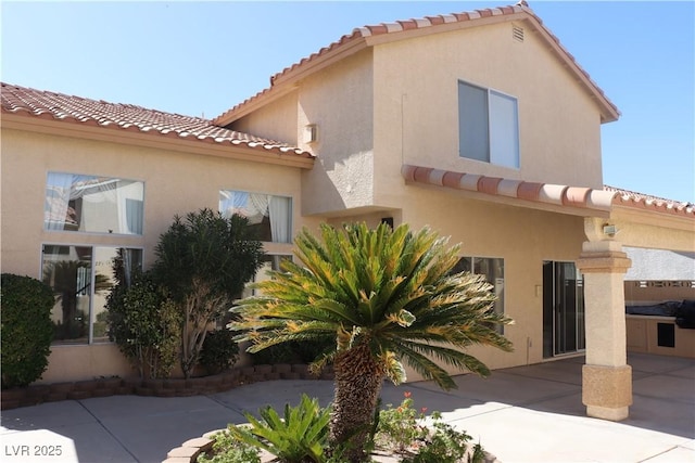 mediterranean / spanish home featuring stucco siding, a patio, and a tiled roof