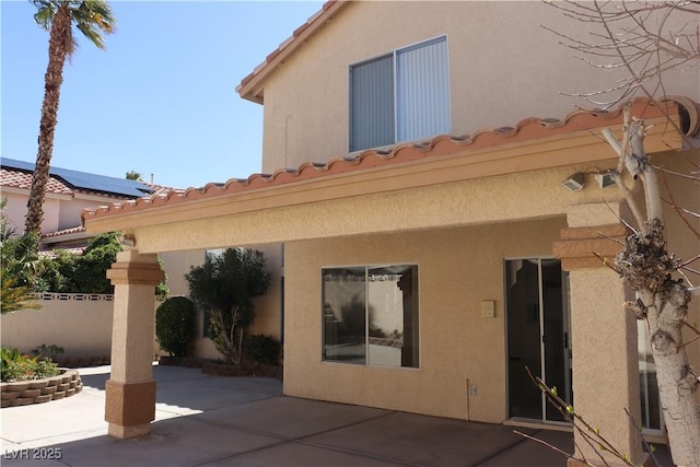 back of property featuring stucco siding, a patio, a tile roof, and fence