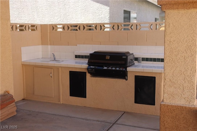 view of patio / terrace with exterior kitchen, fence, and a grill