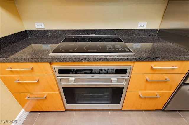 room details featuring stainless steel oven, black electric cooktop, and dark countertops