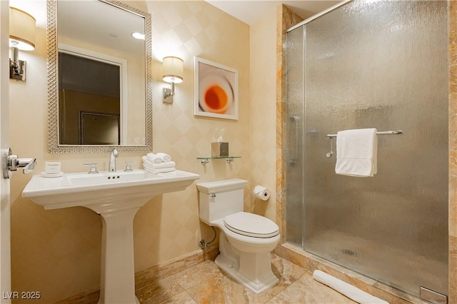 bathroom with a shower stall, toilet, baseboards, and a sink