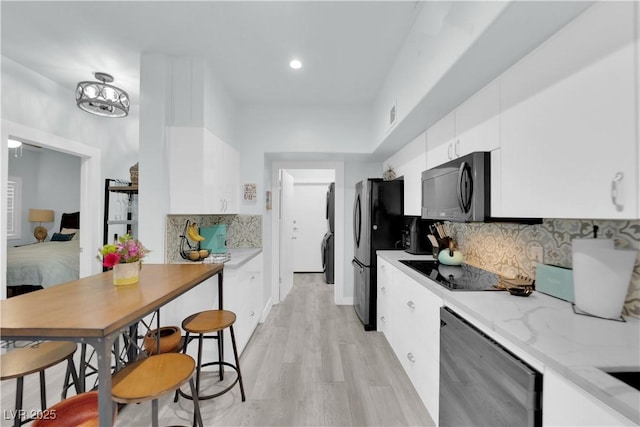 kitchen featuring light stone counters, backsplash, appliances with stainless steel finishes, white cabinets, and light wood finished floors