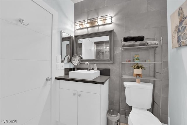 bathroom with vanity, tile walls, and toilet