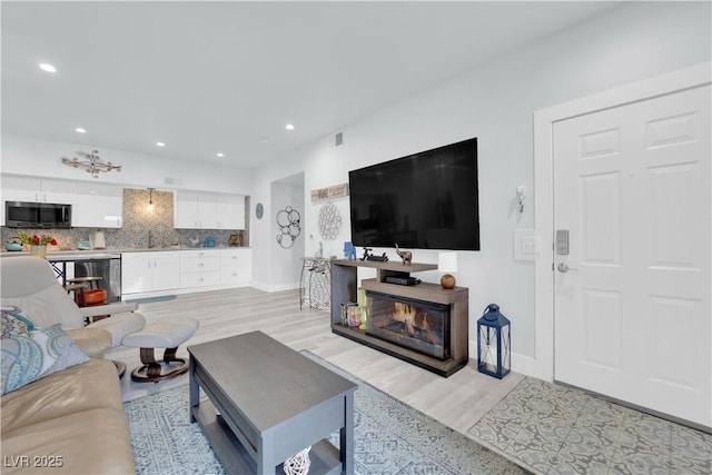 living area with visible vents, recessed lighting, light wood-style floors, and baseboards