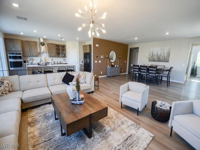 living room featuring visible vents, baseboards, an inviting chandelier, recessed lighting, and light wood-style floors