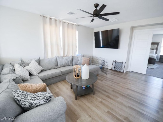 living area with ceiling fan, visible vents, and wood finished floors