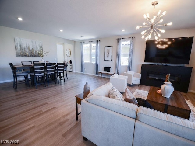 living area with recessed lighting, baseboards, wood finished floors, and a glass covered fireplace