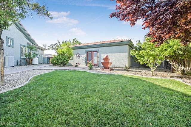 view of front of property with fence, stucco siding, central AC unit, and a front lawn