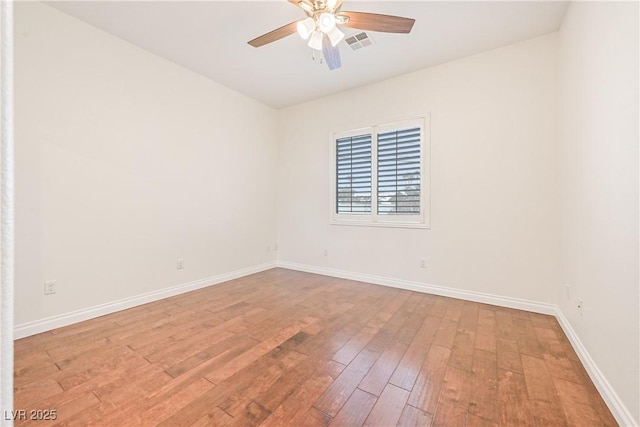 spare room with baseboards, wood-type flooring, a ceiling fan, and visible vents