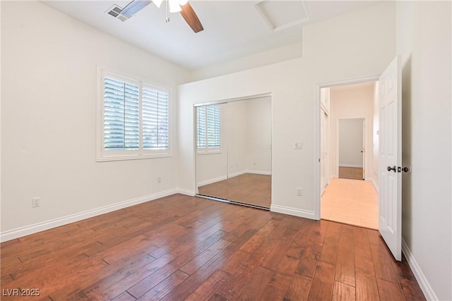 unfurnished bedroom featuring dark wood-style flooring, visible vents, attic access, and a closet
