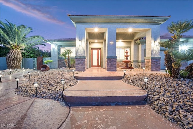 property entrance featuring stone siding and stucco siding