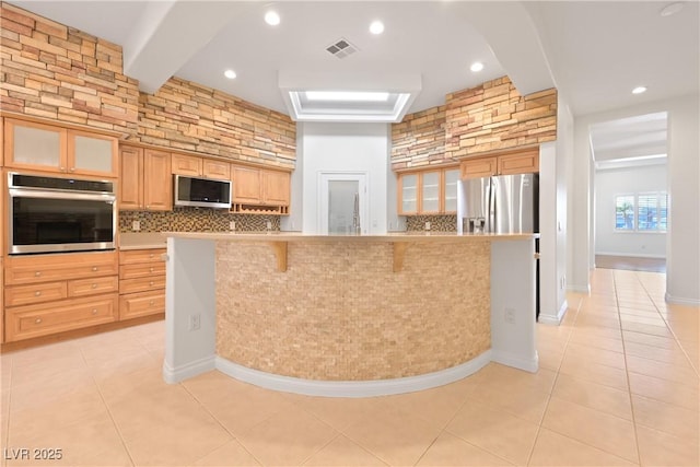 kitchen featuring stainless steel appliances, tasteful backsplash, glass insert cabinets, and light tile patterned flooring