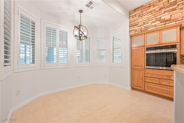 interior space with an inviting chandelier, oven, visible vents, and light tile patterned floors