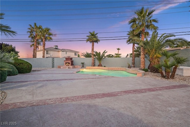 exterior space with a patio, a fenced backyard, a fenced in pool, and a warm lit fireplace