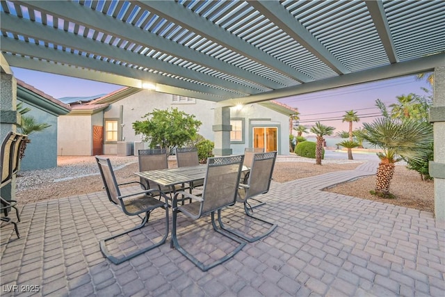 patio terrace at dusk with a pergola and outdoor dining area