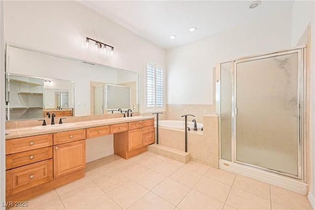 bathroom featuring a bath, a sink, double vanity, tile patterned floors, and a stall shower
