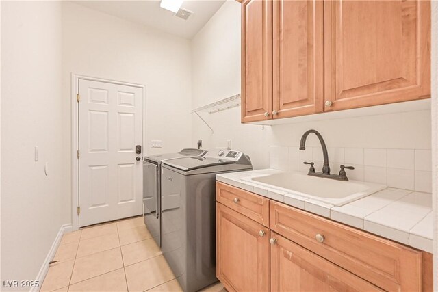 laundry room with baseboards, light tile patterned flooring, washer and clothes dryer, cabinet space, and a sink