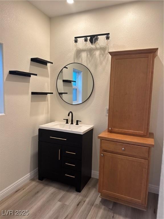 bathroom with baseboards, vanity, and wood finished floors