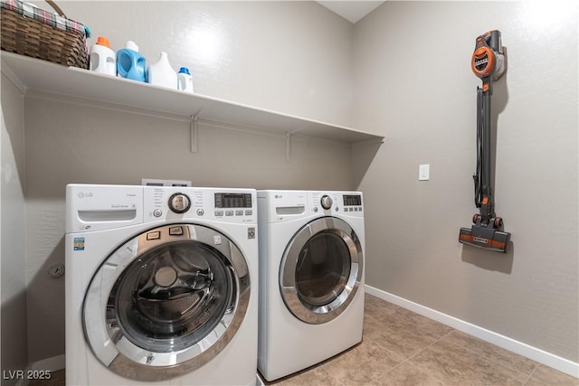 washroom with laundry area, light tile patterned floors, washing machine and dryer, and baseboards