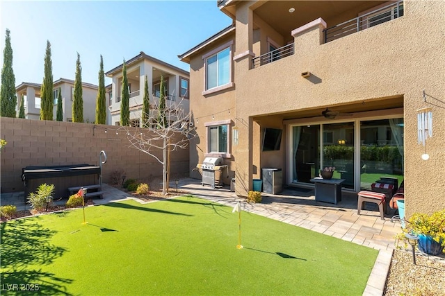 view of yard with a patio area, a balcony, a hot tub, and fence