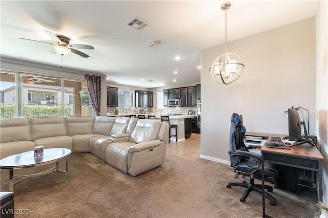 living area featuring visible vents, baseboards, light carpet, ceiling fan with notable chandelier, and recessed lighting