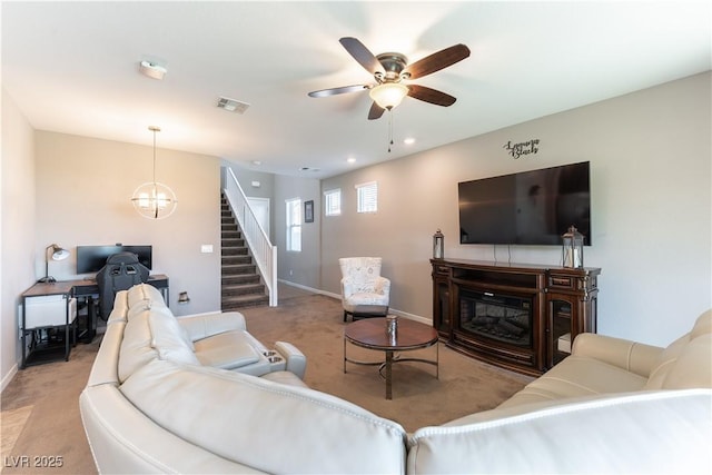 living room with visible vents, light colored carpet, stairs, and a ceiling fan