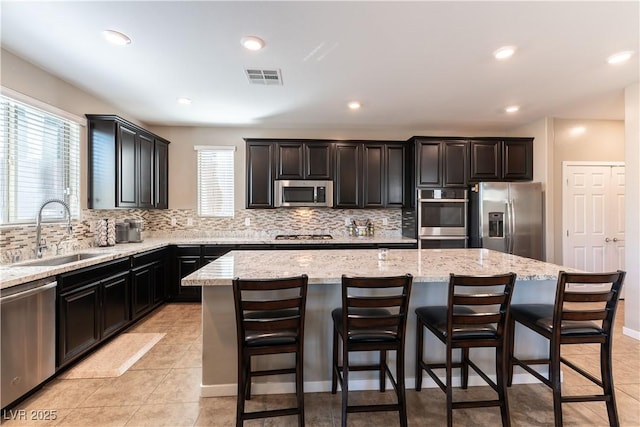 kitchen with tasteful backsplash, visible vents, a kitchen island, stainless steel appliances, and a sink