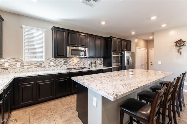 kitchen featuring tasteful backsplash, visible vents, appliances with stainless steel finishes, and a center island