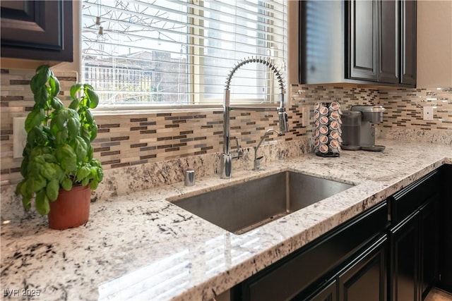 interior details featuring backsplash, light stone countertops, and a sink