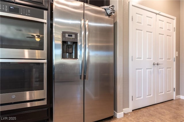 kitchen featuring light tile patterned floors, baseboards, appliances with stainless steel finishes, and ceiling fan