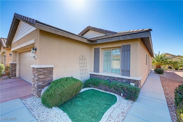 exterior space featuring a tiled roof, a garage, stone siding, and stucco siding