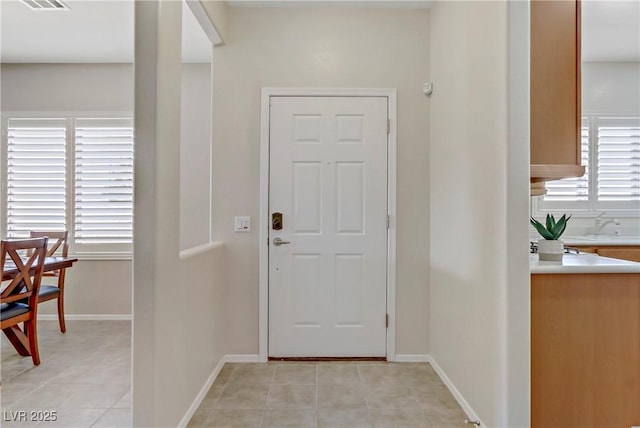 foyer entrance with light tile patterned floors, visible vents, and baseboards