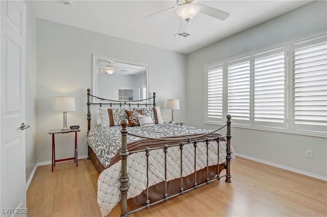 bedroom featuring visible vents, a ceiling fan, baseboards, and wood finished floors