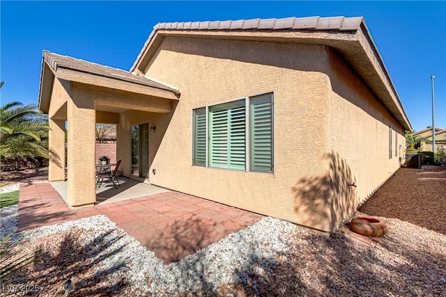 rear view of property featuring stucco siding and a patio