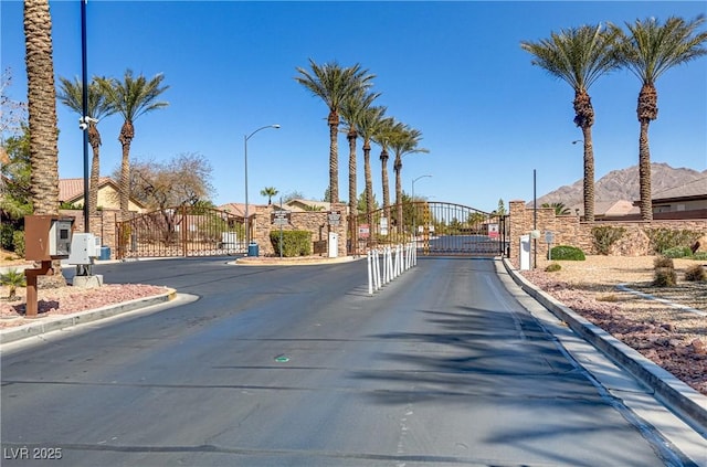 view of street with a gate, curbs, a residential view, and a gated entry