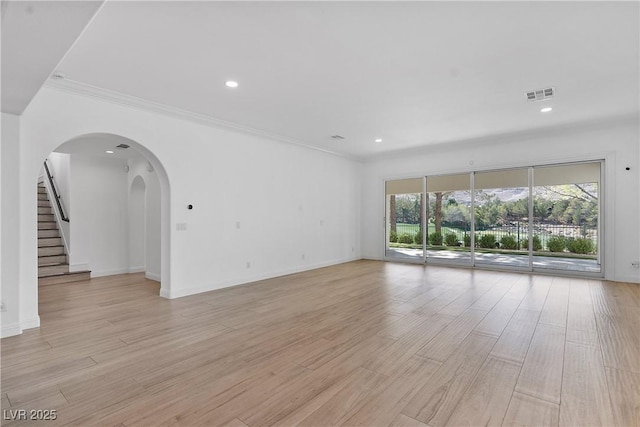 unfurnished living room featuring visible vents, ornamental molding, and light wood finished floors