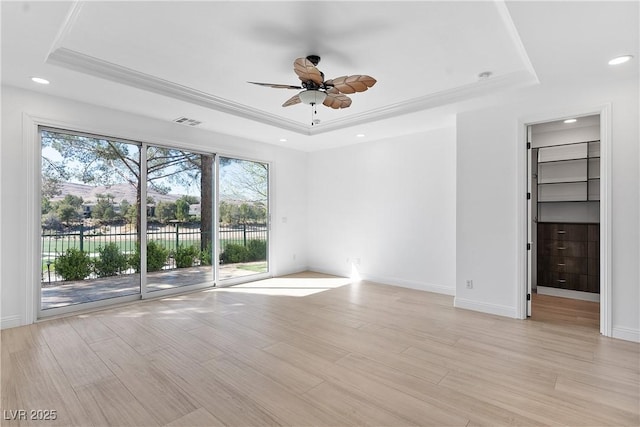 spare room with light wood-type flooring and a tray ceiling