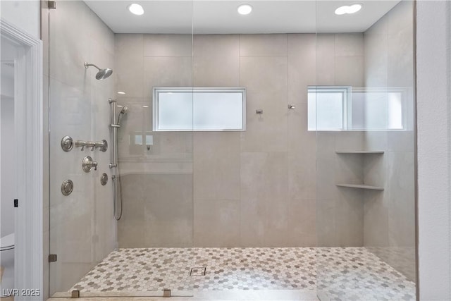 full bathroom featuring toilet, a healthy amount of sunlight, and tiled shower