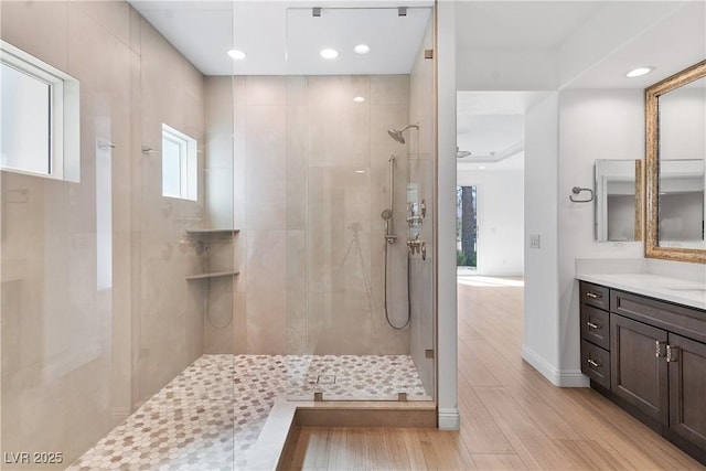 bathroom featuring vanity, wood finished floors, baseboards, recessed lighting, and walk in shower