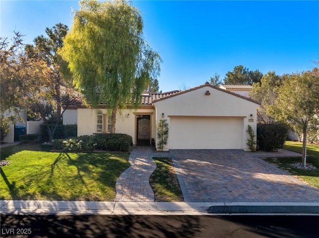 mediterranean / spanish-style home with stucco siding, a tile roof, decorative driveway, a front yard, and an attached garage