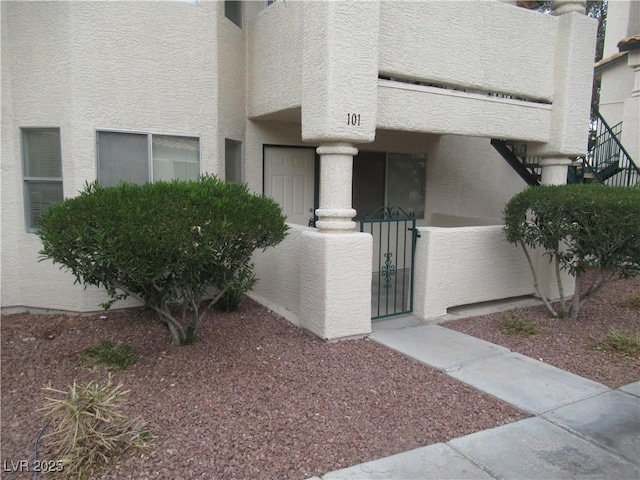 entrance to property featuring stucco siding, fence, and a gate