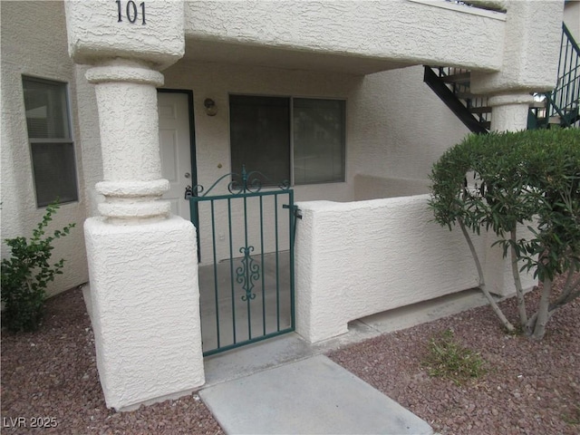 property entrance with stucco siding and a gate