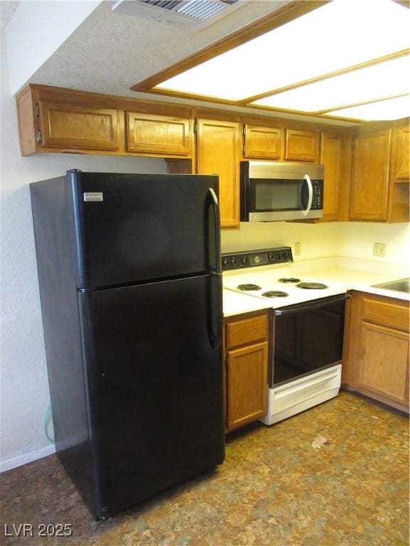 kitchen with white range with electric stovetop, stainless steel microwave, light countertops, and freestanding refrigerator