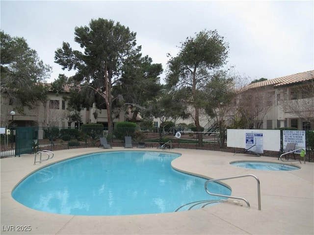 community pool featuring a patio area, a community hot tub, and fence