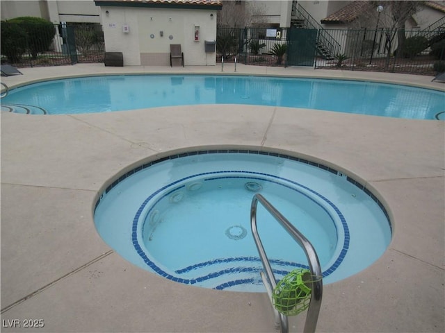 pool featuring a community hot tub and fence